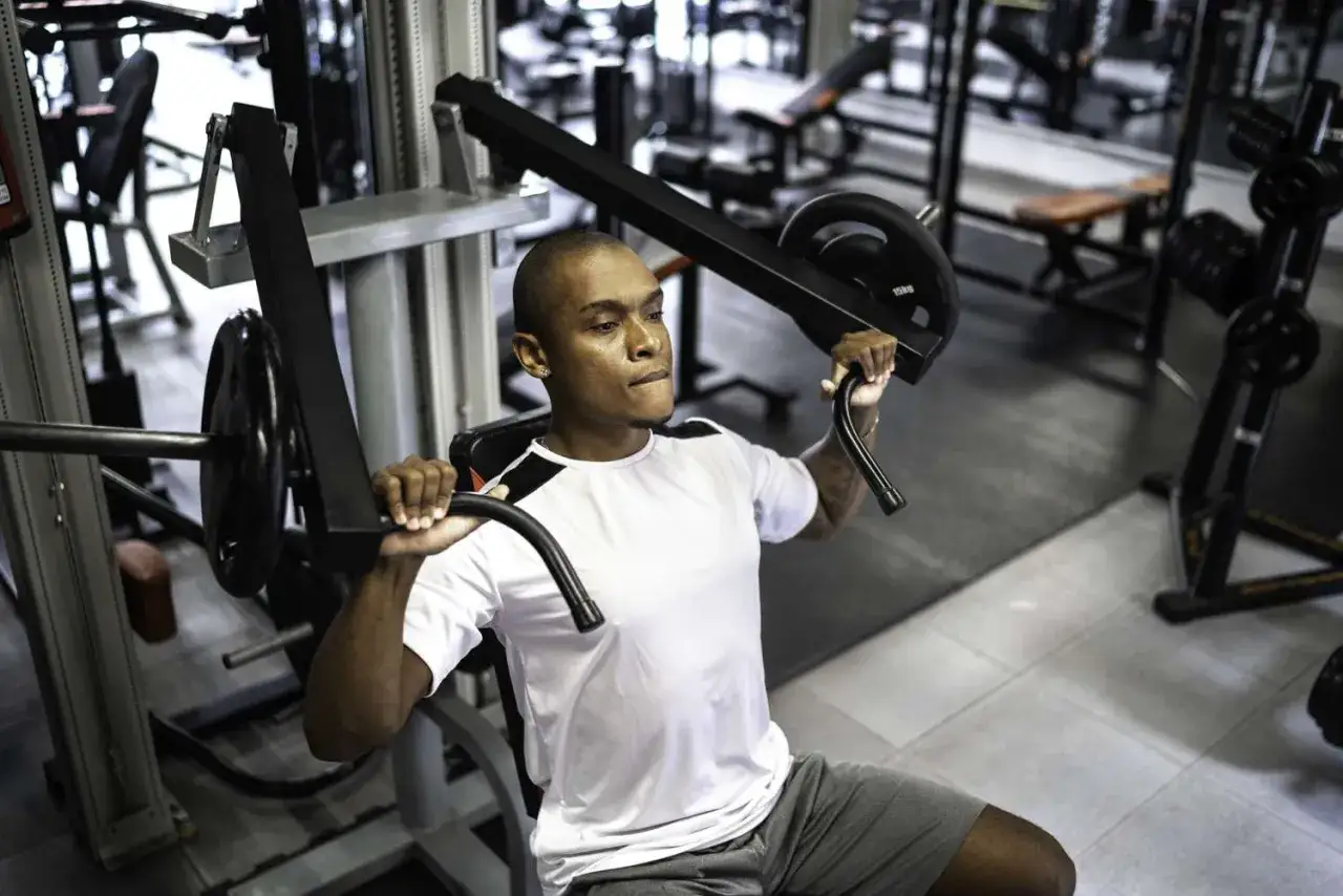 Uomo si allena con la chest press in palestra, concentrato sul movimento.